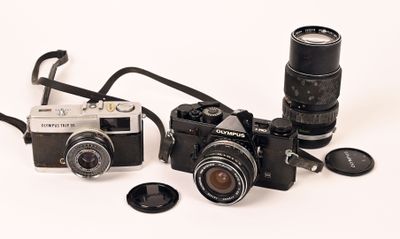 two cameras sitting next to each other on a white surface