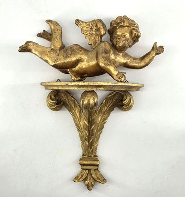 a close up of a gold statue of a cupid on a shelf