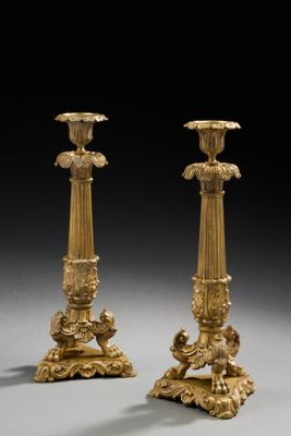 une paire de bougeoirs anciens en laiton sur socles, sur fond gris