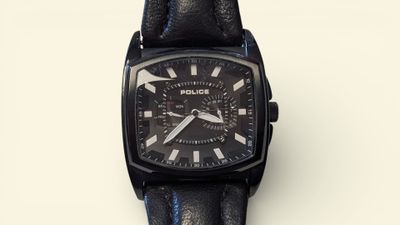 a close up of a black watch on a white surface