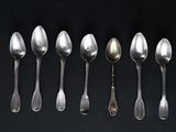 six spoons are arranged in a row on a black surface