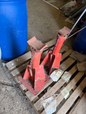a red object on a pallet next to a blue barrel