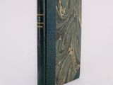 an old book with a green cover sitting on top of a white surface