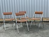 three chairs sitting in front of a metal wall with a brown leather seat