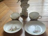 a figurine of a woman sitting on a table next to three bowls and a plate