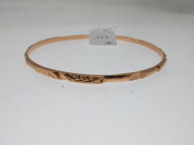 gros plan d'un bracelet en or sur une surface blanche