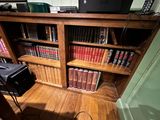 a wooden book shelf with many books on it