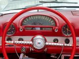 dashboard of a classic car with a red steering wheel and gauges
