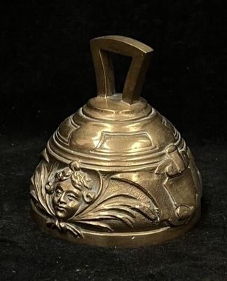 a gold bell with a face on it on a black background
