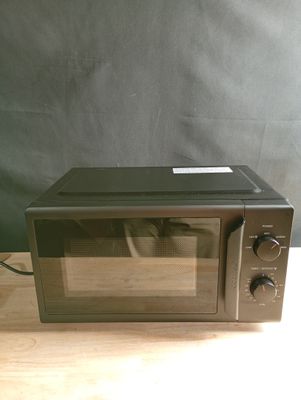 un four à micro-ondes posé sur une table en bois, sur fond noir