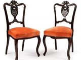 deux chaises avec des coussins rembourrés orange et un dossier sculpté