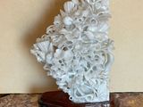a white sculpture of flowers on a wooden stand