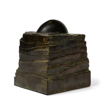 une sculpture représentant une balle posée au sommet d'une pile de livres