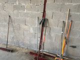 several brooms and rakes leaning against a wall in a garage