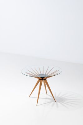 a table with a glass top and wooden legs on a white surface