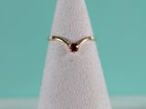 a close up of a gold ring with a red stone on top of a white cone