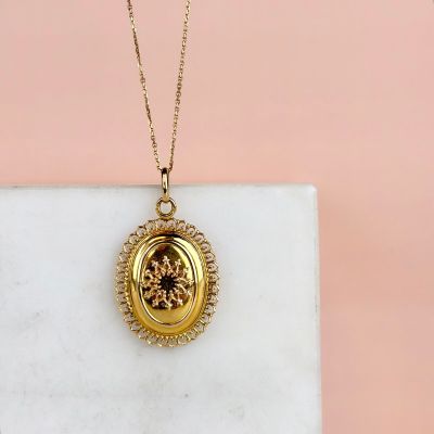 a close up of a gold locke necklace on a marble surface