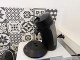 a black coffee pot sitting on top of a microwave oven