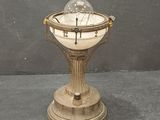 une horloge posée sur un socle, surmontée d'une boule de verre