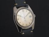 une vieille montre avec un bracelet en cuir noir sur fond noir
