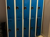 several blue lockers are lined up in a room with a trash can