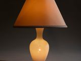 a white lamp with a brown shade sitting on top of a table