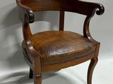 an old wooden chair with a leather seat on a white floor