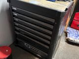 une armoire à outils noire et un tabouret rouge dans un garage