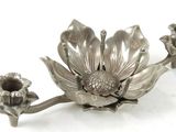 une assiette en argent ornée d'une fleur sur un fond blanc