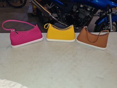 three purses sitting on a table next to a motorcycle