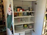 a white cupboard with dishes on it in a kitchen