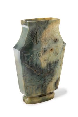 un vase vert orné d'un motif sur fond blanc