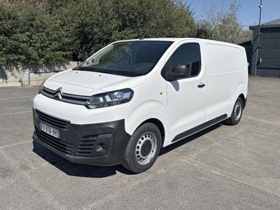 la camionnette blanche est garée sur un parking avec des arbres en arrière-plan