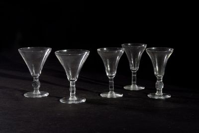 six empty wine glasses lined up in a row on a black surface