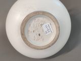 a white vase with a tag on it sitting on a table