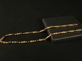 un collier à chaîne dorée présenté dans un coffret noir