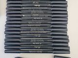 une pile de crayons noirs posée sur une table blanche
