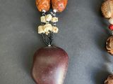two necklaces with wooden beads and red beads on a table