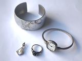 un bracelet, une bague et une montre en argent posés sur une table