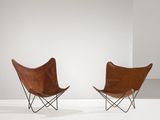 une paire de fauteuils papillon en cuir dans une pièce blanche