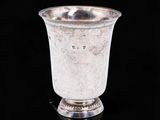 une coupe ancienne en argent posée sur une surface noire, avec un fond noir