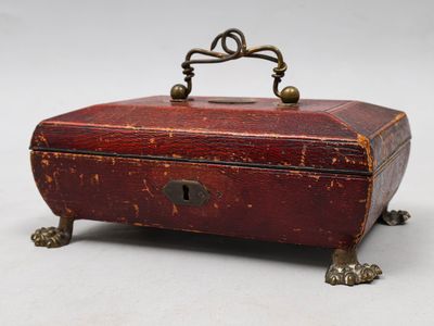une vieille boîte en bois munie d'une poignée, posée sur une surface blanche