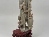 une image représentant une statue d'un homme tenant un pot sur un rocher