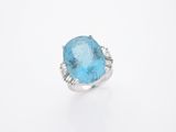 une bague avec une topaze bleue ovale et des diamants, sur fond blanc