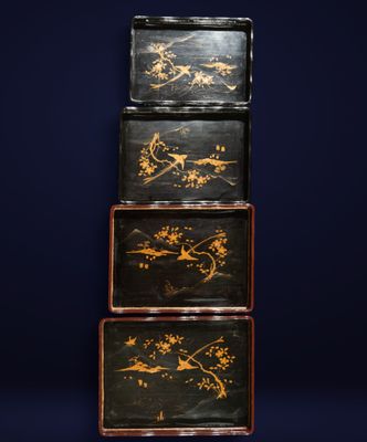 three black and gold painted boxes stacked on top of each other