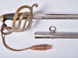 une épée avec une poignée en métal et deux autres objets posés sur une surface blanche