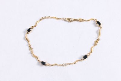 un gros plan d'un bracelet en or orné de perles noires sur fond blanc