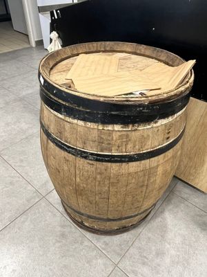 un tonneau en bois posé par terre à côté d'un morceau de bois