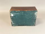 an old green box with a wooden top sitting on top of a white surface