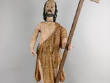 wooden statue of a man holding a cross and a wooden pole